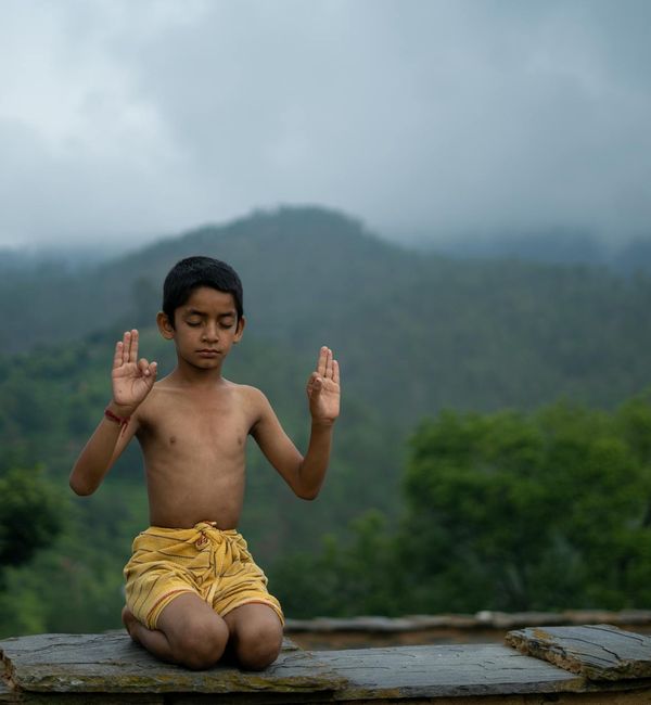 Person sitting in a calm, meditative pose in a serene environment.